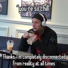 a man sitting at a table with headphones on eating food and drinking from a cup