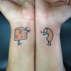 two people with tattoos on their arms holding up their hands and one has a piece of cheese in the other hand