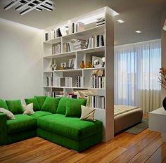 a green couch sitting in front of a book shelf