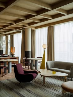 a living room filled with lots of furniture and large windows covered in draping