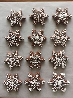 twelve snowflake cookies are arranged on a sheet of paper