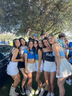 a group of young women standing next to each other in front of a car at a park