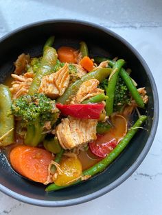 a bowl filled with meat and veggies on top of a white countertop