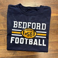 a t - shirt that says bedford football on the front, and an image of a football in the middle