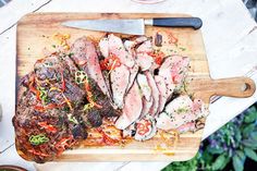 a cutting board topped with sliced meat and vegetables