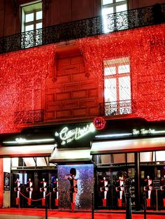 a building with red lights on it and people standing in the doorways at night