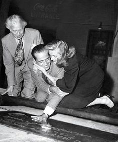 an old black and white photo of two people on a bench with chalk written on it