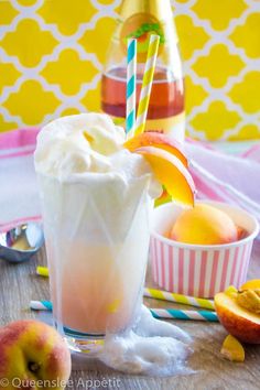 a glass filled with ice cream next to some peaches and an orange juice bottle