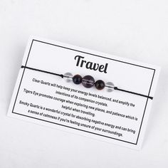 two bracelets with words on them sitting on a white card that says, travel