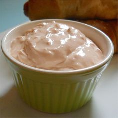 a green bowl filled with cream next to some croissants