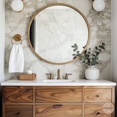 a bathroom vanity with marble counter top and round mirror above it, along with two white vases