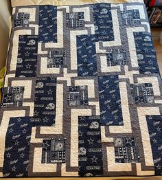 a blue and white quilt on top of a bed with a bookcase in the background