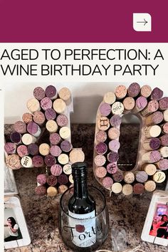 a bottle of wine sitting on top of a table next to a cork letter and photos