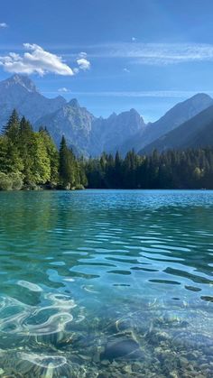 the water is crystal blue and clear with mountains in the background