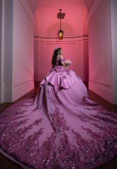 a woman in a pink gown is sitting on the floor with her hands behind her back