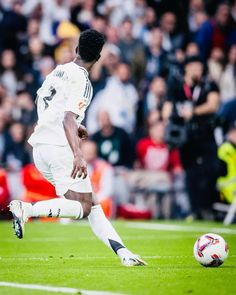 a man kicking a soccer ball on top of a field