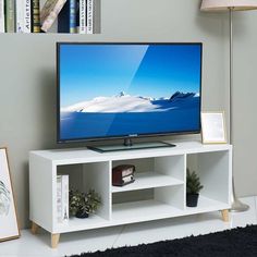 a flat screen tv sitting on top of a white entertainment center next to a lamp