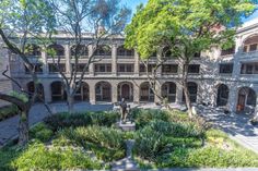 the courtyard of an old building with many trees and bushes