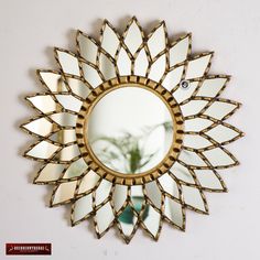 a mirror with a flower on it is hanging on the wall next to a potted plant