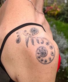 the back of a woman's shoulder with a tattoo design on her left arm