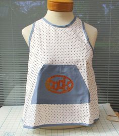 an apron on a mannequin with the word monogrammed in orange and blue