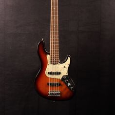 an electric bass guitar hanging on the wall in front of a black background with no strings