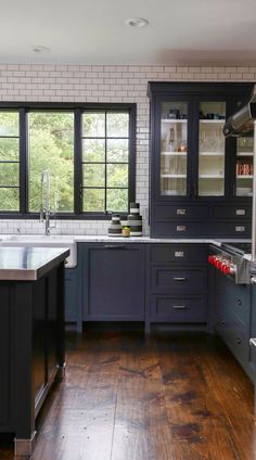 a large kitchen with wooden floors and blue cabinetry, along with stainless steel appliances