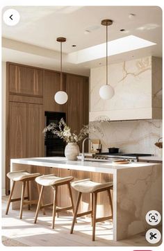 a kitchen with marble counter tops and stools in front of an island that has three lights hanging from the ceiling