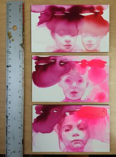 three paintings are displayed on a table with a ruler in front of them and one is pink