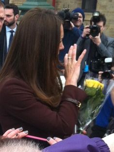 the woman is holding her hand out to greet someone in front of some people with cameras