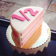 a pink and white cake sitting on top of a table next to a glass window