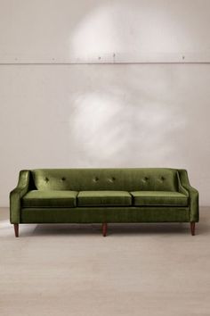 a green couch sitting in front of a white wall