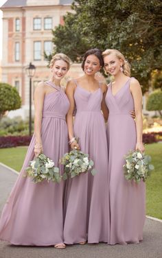 three bridesmaids pose for a photo in front of a building