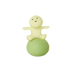 a small plastic toy sitting on top of a green ball with its arms spread out