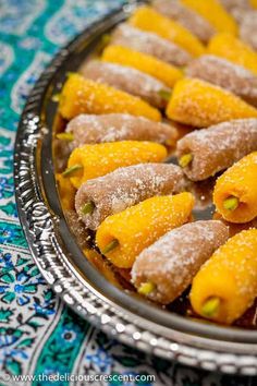 some food is on a silver plate and has powdered sugar on it with the words persian foot mulberry marzipan candy