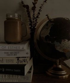 a stack of books sitting next to a globe on top of a table