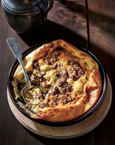 a pizza sitting on top of a wooden table next to a cup