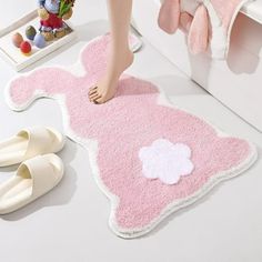 a person standing on a pink rug next to white shoes and a teddy bear toy