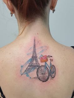 the back of a woman's neck with a tattoo of a bicycle and eiffel tower