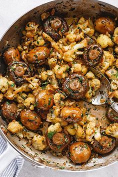 a skillet filled with mushrooms and other food on top of a white table cloth