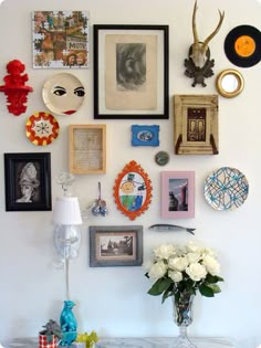 a table with some flowers and pictures on the wall above it, along with two chairs