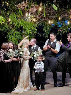 a group of people standing around each other in front of a tree with lights on it