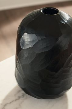 a black vase sitting on top of a white table