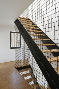 an empty room with wood flooring and black railing on the stair case next to a window