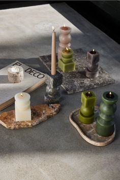 some candles are sitting on a table next to an open book and two small vases