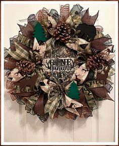 a christmas wreath hanging on the front door with pine cones and plaid ribbon around it