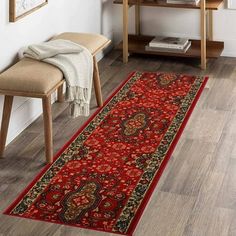 a long red rug in the corner of a room with a wooden table and chair