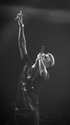 a man is holding his cell phone up in the air while standing on stage at a concert