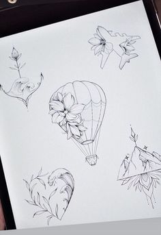 a person is holding a piece of paper with drawings on it, including flowers and hot air balloons