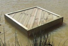 a wooden dock sitting in the middle of a flooded area with grass growing around it